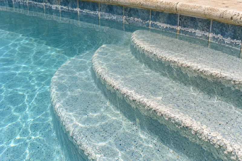 White calcium scale on pool steps and a dull film on the finish