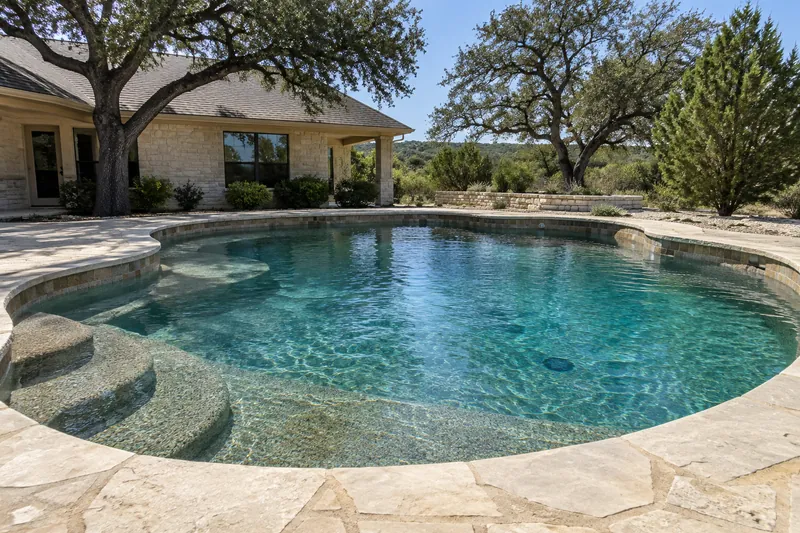 Backyard pool with an earth-tone pebble finish and deep teal water