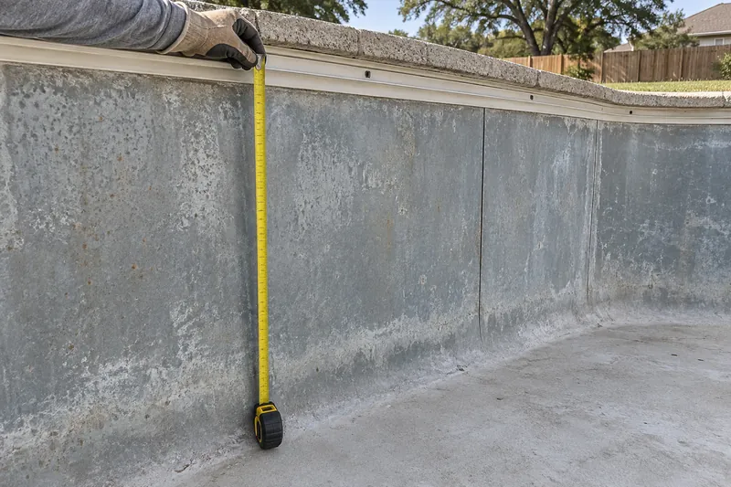 Tape measure run from the liner track to the floor of a drained pool